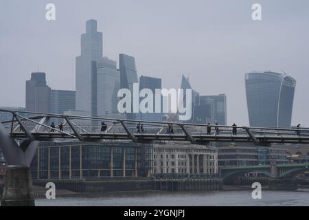 Die Menschen laufen über die Millennium Bridge in London, während der Himmel grau wird, weil der Druck über Großbritannien Feuchtigkeit in der Nähe der Erdoberfläche einschließt und so hartnäckige Wolken oder, im Wetterverständnis, „antizyklische Dunkelheit“ erzeugt. Hoher Druck führt zu wenig oder gar keinem Wind, der die Wolke sonst umherbewegen und aufbrechen würde. Bilddatum: Freitag, 8. November 2024. Stockfoto