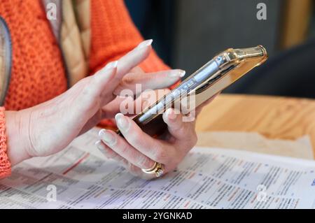 Nahaufnahme einer Frau, die mit ihrem Smartphone interagiert und die Verwendung mobiler Geräte bei täglichen Aktivitäten hervorhebt, die sich hervorragend für Technik und Kommunikation eignen Stockfoto