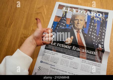 Paris, Frankreich - 7. November 2024: Ein neugieriger Kleinkind zeigt sich beim Anblick einer Le Figaro-Schlagzeile über Donald Trumps politisches Comeback, der frühes Interesse an Weltnachrichten zeigt Stockfoto