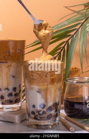 Boba dalgona Kaffee. Trendiges asiatisches Latte-Morgengetränk mit Instant-Kaffee und Tapioka-Perlkugeln, thailändisches Schaumcocktail-Glas im Sommer in der Sonne Stockfoto