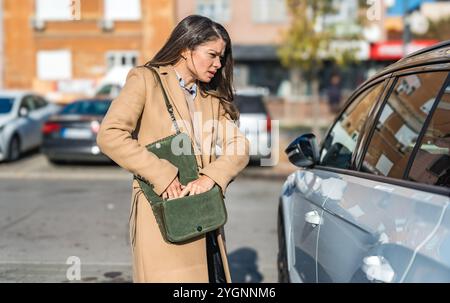 Junge gestresste Geschäftsfrau, Fahrer, auf dem Parkplatz in der Nähe ihres Autos, kann keine Schlüssel finden, wütend und besorgt suchen, denken, es wäre gestohlen. Opfer von Stockfoto