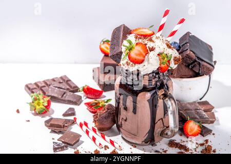 Milchshake mit doppeltem Schokoladengeschmack. Verrückter Shake mit Brownie-Geschmack, Schokoladensoße, Schlagsahne und frischen Erdbeeren, sommerlich süßes, geladenes Swe Stockfoto