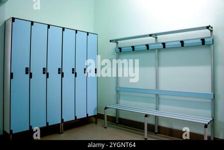 Leerer, sauberer Umkleideraum mit hellblauen Schließfächern und Bank, perfekt für Sport oder Fitnessstudio. Moderne, gut beleuchtete Einrichtung bietet Privatsphäre und Sicherheit Stockfoto