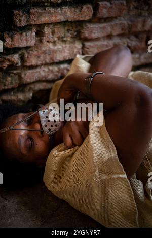 Porträt einer schwarzen Frau, gekettet und mit einer eisernen Maske über dem Mund, die auf dem Boden liegt. Sklaverei in Brasilien. Darstellung der Sklavin Anastacia. Stockfoto