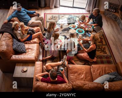 Eine Familie versammelt sich in einem gemütlichen Wohnzimmer und genießt Snacks, Spiele und eine gute gemeinsame Zeit. Die warme Atmosphäre strahlt gemeinsame Momente aus. Stockfoto