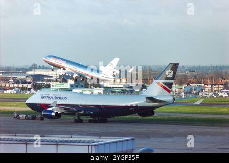 British Airways Boeing 747 Jumbo Jet Jet Flugzeug G-CIVJ in der Landor Farbgebung wird von einem Schlepper gezogen, wobei American Airlines McDonnell Douglas MD-11 Anfang 2000 vom Flughafen London Heathrow, Großbritannien, startete. 747 G-CIVJ wurde am 11. Februar 1997 neu an BA geliefert und am 15. April 2020 an Kemble zurückgezogen. American Airlines stellte ihre Flotte von MD-11-Flugzeugen 2001 aus. Stockfoto