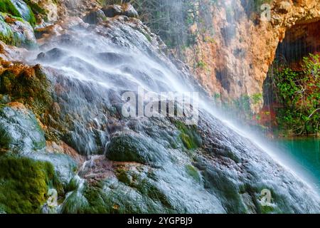 Das Wasser fließt anmutig über üppige, moosbedeckte Felsen und schafft eine friedliche Atmosphäre in der Umgebung der Natur. Stockfoto