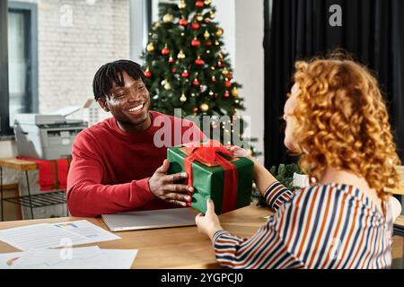 Kollegen teilen einen Moment des Glücks, während sie Geschenke in einer fröhlichen Weihnachtskulisse austauschen Stockfoto