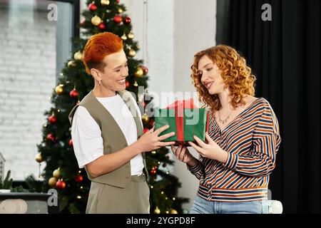 Zwei fröhliche Kollegen teilen einen besonderen Moment, während sie während einer Weihnachtsfeier Geschenke austauschen. Stockfoto