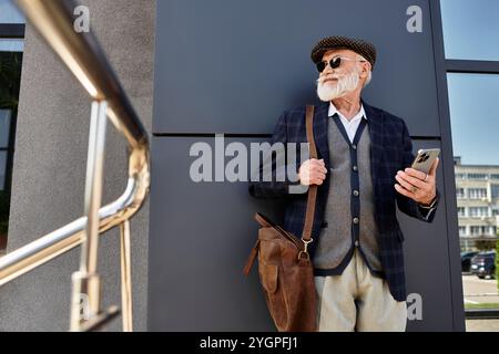 Ein angesagter Seniorenmann steht selbstbewusst vor einem zeitgenössischen Gebäude und zeigt seinen herbstlichen Stil. Stockfoto