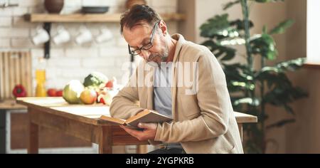 Stattliche reifer Mann lesen Kochbuch in der Küche Stockfoto