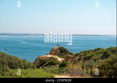 Wanderer genießen einen atemberaubenden Blick von einer Küstenklippe mit Blick auf den weitläufigen atlantik unter einem klaren blauen Himmel Stockfoto