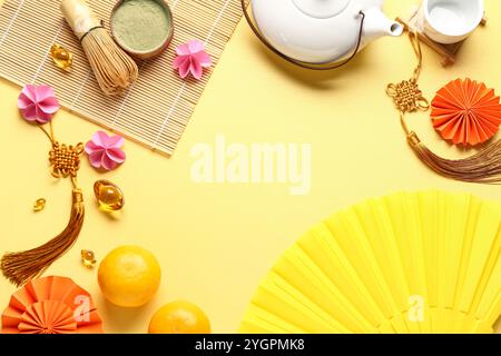 Teekanne mit Mandarinen, Schüssel mit Matcha-Pulver, chasen und orientalischen Symbolen auf gelbem Hintergrund. Neujahrsfeier Stockfoto