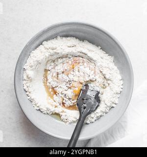 Blick von oben auf den Mooncake-Teig, der gemischt wird, Blick von oben auf den hausgemachten Mooncake-Teig in einer grauen Schüssel, Herstellung von Mooncakes für das Festival in der Mitte des Herbstes Stockfoto