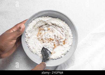 Blick von oben auf den Mooncake-Teig, der gemischt wird, Blick von oben auf den hausgemachten Mooncake-Teig in einer grauen Schüssel, Herstellung von Mooncakes für das Festival in der Mitte des Herbstes Stockfoto