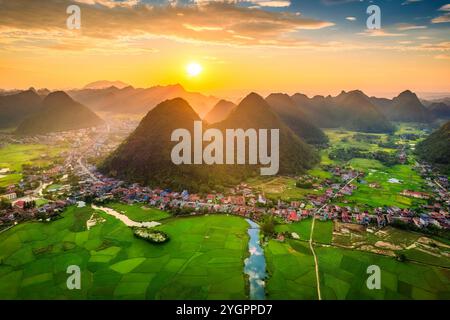 Blick aus der Vogelperspektive auf den goldenen Sonnenuntergang über dem Bac Son Valley mit Bergen, üppigen Reisfeldern und einem traditionellen Dorf auf dem Land in lang Son, Vietnam Stockfoto