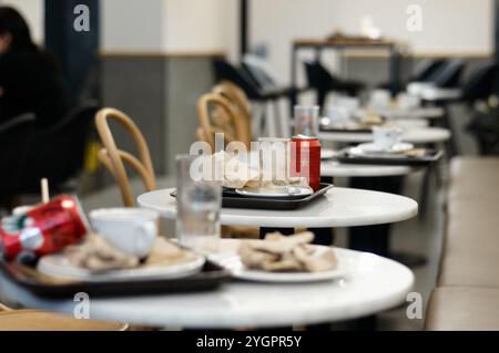 Viladecans. Spanien - 8. November 2024: Die Szene einer Cafeteria nach dem Mittagessen mit Tischen, die mit leeren Tassen und Tellern verstreut sind. Das Bild reflektiert t t Stockfoto