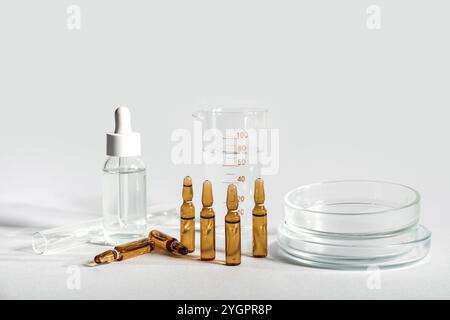 Medizinische Ampullen mit Laborglas und Petrischale auf grauem Hintergrund Stockfoto