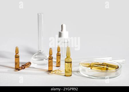 Medizinische Ampullen mit Laborglas und Petrischale auf grauem Hintergrund Stockfoto