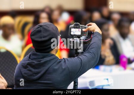 Kameramann nimmt ein Ereignis mit einer Kamera auf einem Gimbal auf, trägt einen Hoodie und eine Mütze Stockfoto