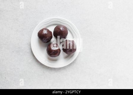 Blick von oben auf rote Bohnenpaste Kugeln in einer weißen Schüssel, Blick von oben auf süße Adzuki Bohnenpaste Kugeln in einer weißen Platte, Prozess der Herstellung von Mondkuchen Stockfoto