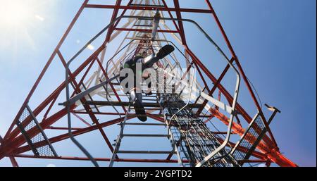 Techniker klettert auf einen Kommunikationsturm, um eine Antenne, Antenne, unten zu reparieren Stockfoto