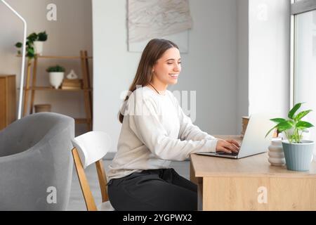 Programmiererin, die mit Laptop am Schreibtisch im Zimmer arbeitet Stockfoto