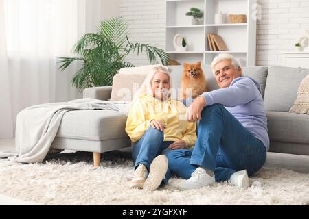 Glückliches Seniorenpaar mit süßem Pommerschen Hund zu Hause Stockfoto