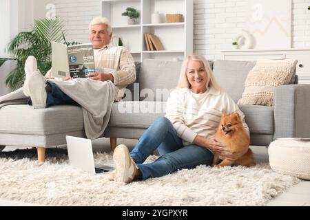 Glückliches Seniorenpaar mit süßem Pommerschen Hund zu Hause Stockfoto