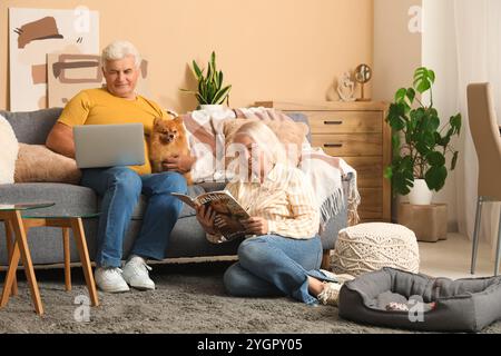 Glückliches Seniorenpaar mit süßem Pommerschen Hund, der zu Hause ruht Stockfoto