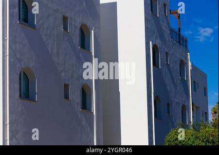 Das Gebäude verfügt über weiße Wände mit abgerundeten Fenstern, die das Sonnenlicht in einer bezaubernden Küstenlandschaft reflektieren. Stockfoto