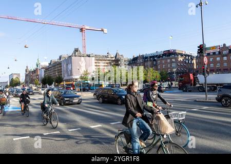 Männer und Frauen, die mit ihren Fahrrädern durch das Stadtzentrum von Kopenhagen fahren, auf einem speziellen Radweg neben Kraftfahrzeugen Stockfoto