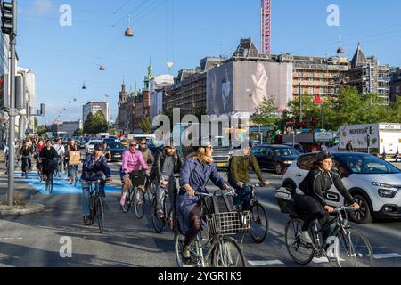 Männer und Frauen, die mit ihren Fahrrädern durch das Stadtzentrum von Kopenhagen fahren, auf einem speziellen Radweg neben Kraftfahrzeugen Stockfoto