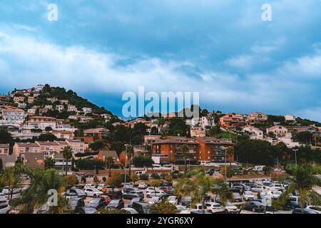 Bezaubernde Aussicht auf eine friedliche spanische Stadt, wo bunte Häuser unter einem dramatischen bewölkten Himmel auf üppiges Grün treffen Stockfoto