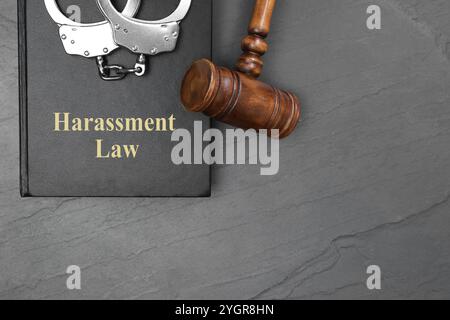Belästigungsgesetzbuch, richterlicher Hammer und Handschellen auf grauem Tisch, Draufsicht. Leerzeichen für Text Stockfoto