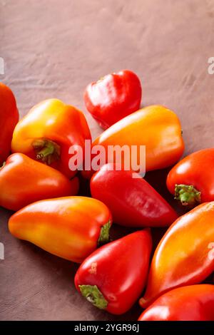 Frischer reifer roter und oranger Paprika auf brauner Tonoberfläche, lebendiges Gemüse Stockfoto