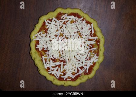 Glutenfreie und milchfreie Pizza, Kruste mit Pizzasauce auf einem Holztisch, Speisenvorbereitung, Vorbereitung auf das Abendessen, Zöliakie-Krankheit, Glutenalternative, alt Stockfoto