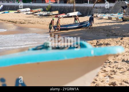 Am Strand von Rio Vermelho werden Fischer gesehen, die ein Fischerboot auf das Meer schieben. Salvador, Bahia. Stockfoto