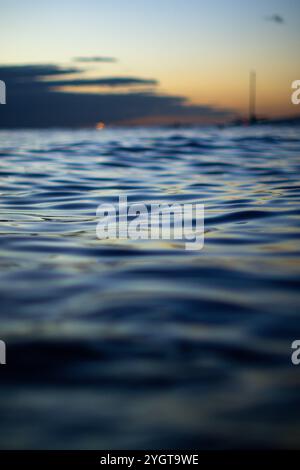 Das Sonnenlicht verblasst und wirft ein warmes Licht auf den plätschernden Ozean, Waikiki Stockfoto