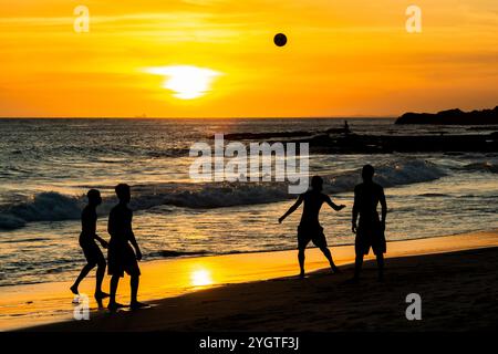 Salvador, Bahia, Brasilien - 6. Dezember 2019: Menschen werden bei Sonnenuntergang am Strand von Farol da Barra in Salvador, Bahia, beim Fußballspielen beobachtet. Stockfoto