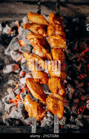 Saftig marinierte Hähnchenflügel gegrillt über heißer Holzkohle für das ultimative Grillerlebnis Stockfoto