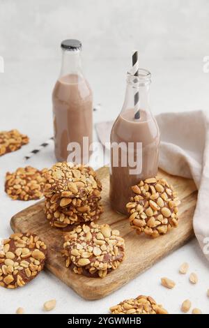 Ein Haufen traditioneller portugiesischer Erdnusskekse, bekannt als Bolachas de Amendoim auf dem Holzbrett mit zwei Flaschen Kakaomilch und einer Serviette auf dem gr Stockfoto