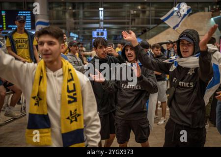 Lod, Israel. November 2024. Maccabi Tel Aviv Fans jubeln, als sie auf einem Flug von Amsterdam am Flughafen Ben Gurion ankommen. Israelische Fußballfans wurden vor dem Fußballspiel der UEFA Europa League zwischen Ajax Amsterdam und Maccabi Tel Aviv am Donnerstag von pro-palästinensischen Demonstranten angegriffen. Quelle: Ilia Yefimovich/dpa/Alamy Live News Stockfoto