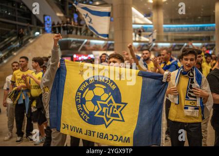 Lod, Israel. November 2024. Maccabi Tel Aviv Fans jubeln, als sie auf einem Flug von Amsterdam am Flughafen Ben Gurion ankommen. Israelische Fußballfans wurden vor dem Fußballspiel der UEFA Europa League zwischen Ajax Amsterdam und Maccabi Tel Aviv am Donnerstag von pro-palästinensischen Demonstranten angegriffen. Quelle: Ilia Yefimovich/dpa/Alamy Live News Stockfoto