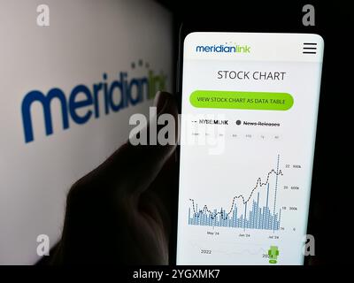 In dieser Abbildung hält eine Person ein Mobiltelefon mit der Website des US-amerikanischen Finanzsoftware-Unternehmens MeridianLink Inc. Vor dem Logo. Stockfoto