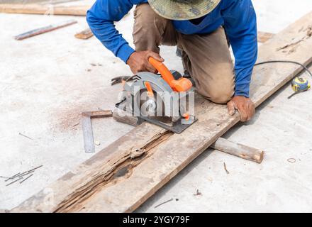 Der Zimmermann verwendete die Kreissäge, um das Holzblech auf der Baustelle zu schneiden. Stockfoto