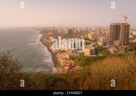 Die Küste von Dakar in Senegal, Westafrika, mit Baustelle, Gebäuden und Stadtteilen während des subtilen rosafarbenen Sonnenuntergangs. Stockfoto