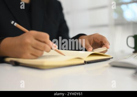 Nahaufnahme einer Geschäftsfrau, die in einem Journal schreibt, um sich an eine Aufgabe oder einen Plan für ein Unternehmensprojekt zu erinnern Stockfoto