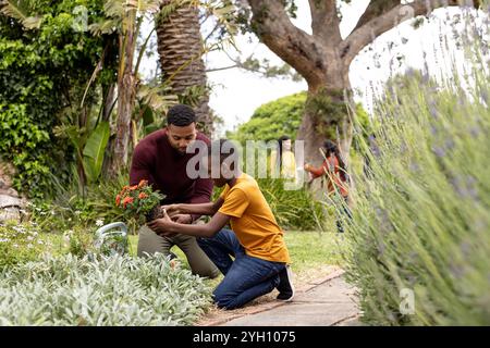 Vater und Sohn Pflanzen Blumen zusammen im Garten und genießen die gemeinsame Familienzeit im Freien Stockfoto