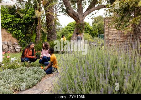 Gemeinsame Familie, die im üppigen Hinterhof Gartenarbeit leistet, die Natur genießt und sich im Freien verbündet Stockfoto